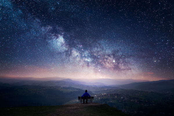 Person sitting on a bench beneath the night sky